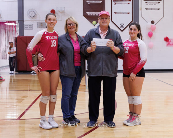 Coach and players smiling holding a check to support breast cancer